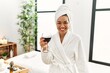 © Krakenimages.com - Young latin woman wearing bathrobe toasting with wine at beauty center