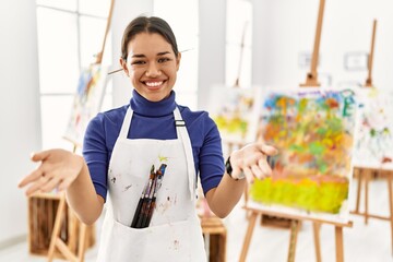 Canvas Print - Young brunette woman at art studio smiling cheerful offering hands giving assistance and acceptance.