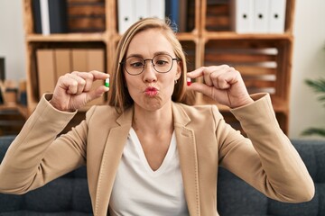 Canvas Print - Young blonde woman holding pills at therapy making fish face with mouth and squinting eyes, crazy and comical.