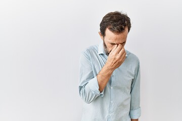 Sticker - Middle age hispanic man with beard standing over isolated background tired rubbing nose and eyes feeling fatigue and headache. stress and frustration concept.