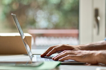 Business man typing on laptop keyboard at office desk background. Male user hands remote working on computer, searching on internet, communicating in web, learning online. Close up side view