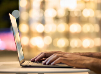 business man hands typing on laptop keyboard on night lights background. male user remote working la