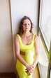 © Tatyana - Young woman in yellow sportswear posing in sports club hall at window indoors. Sporty fit girl portrait. Smart elegant woman sitting on windowsill thoughtful. Top and leggings suit. Woman alone