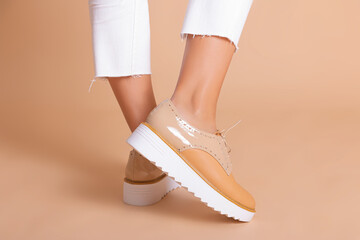 Legs of a woman close-up, sneakers with design in studio on cream background.