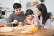© Pormezz - happy family together. Asian parent eating breakfast with little son in the kitchen.