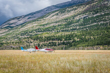 Two Airplanes Tied Down At The Jasper Airstrip Near Jasper, Alberta With Mountains In The Background