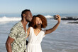 © WavebreakMediaMicro - Happy couple taking a selfie on the beach
