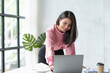 © amnaj - Beautiful Asian businesswoman working on a desk with a laptop with a smiling face while looking at the document received in the office.