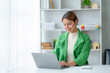 © amnaj - Beautiful Asian businesswoman working on a desk with a laptop with a smiling face while looking at the document received in the office.