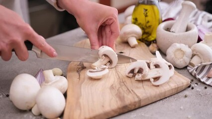 Canvas Print - Woman cuts champignon mushrooms with a knife on a wooden cutting board