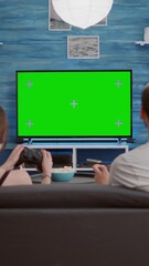 Canvas Print - Static tripod shot of young woman and boyfriend gaming online having fun on green screen competing against each other. Couple of gamers spending free time playing console game on chroma key display.