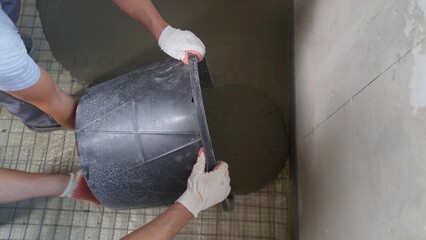 Poster - Floor repair, liquid mixture, leveling flooring. Construction workers pour out mortar of cement from bucket. Workers pour the floor in the room with a mortar mixture. Self-leveling floor.