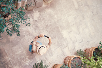 Wall Mural - Travel and active lifestyle concept. Top view of traveller walking in ancient town holding smartphone.