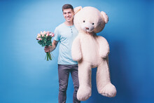 Saint Valentine's Day Concept. Handsome Young Man Holding Big Teddy Bear Against Blue Wall.