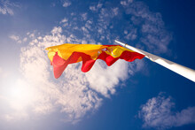 Flag Of Spain With Red And Yellow Colors Waving In The Wind During A Sunny Day With Blue Sky
