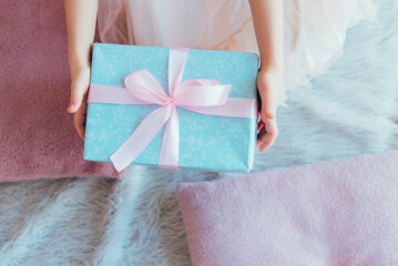 Wall Mural - girl holding a gift box with a pink ribbon in her hands