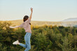 © SHOTPRIME STUDIO - Happy woman jumping up from happiness in nature with her back to the camera with a beautiful mountain view