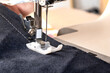 Sewing machine foot with a needle sews fabric. Close-up. Place for text