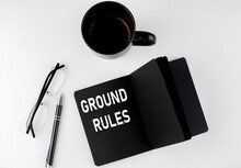 GROUND RULES Written Text In Small Black Notebook With Coffee , Pen And Glasess On White Background. Black-white Style