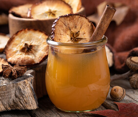 Wall Mural - Glass of apple cider with cinnamon stick and dried apple chip