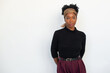 © KAMPUS - Portrait of beautiful African American woman. Female model in black long sleeve shirt and trousers standing against white background, looking at camera. Portrait, beauty, studio photoshoot concept