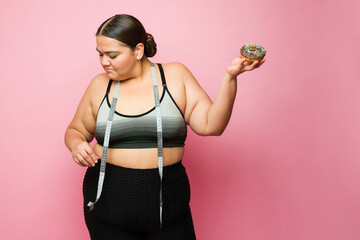 Wall Mural - Happy fitness overweight woman on a diet eating junk food