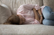 © fizkes - Depressed unhappy ill young woman lying on couch in embryo pose, suffering from belly ache, spasm, miscarriage symptoms, feeling strong pain. Health problems, emotional crisis