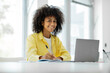 © Home-stock - Cheerful black female freelancer looking at camera and working from home sitting at work desk in front of laptop copy space