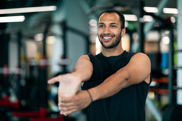 Wall Mural - Warming Up. Young Handsome Black Male Athlete Stretching Arm Muscles At Gym