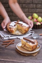 Wall Mural - Homemade pie with apples and cinnamon on a dark wooden background. Homemade autumn pastries: a piece of apple pie and ripe apples on a wooden table.