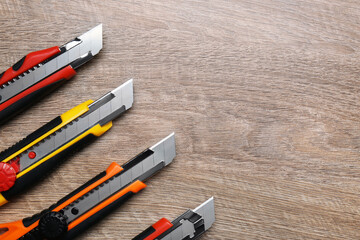 Canvas Print - Many different utility knives on wooden table, flat lay. Space for text