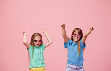 Cute adorable children having fun together with bright colorful t-shirts isolated on pink background