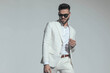 © Viorel Sima - bearded fashion man wearing white suit and sunglasses and looking down