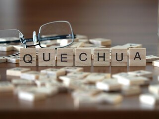 Wall Mural - quechua word or concept represented by wooden letter tiles on a wooden table with glasses and a book