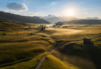 Fototapete - Sunrise with fog and mist in the Dolomites mountains of the Alps in Italy. High mountains pastures with cottages and roads. 