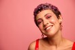 © SHOTPRIME STUDIO - Fashion portrait of a woman with a short haircut of purple color and a smile with teeth in a red top on a pink background dancing happily