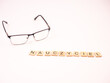 Nauczyciel - napis z drewnianych literek na białym tle, okulary 