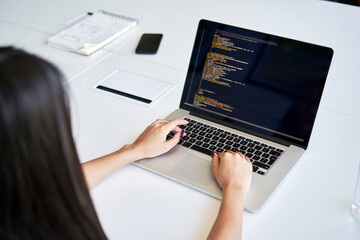 Female programmer writing code at office using laptop