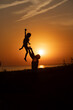 © IrinaStrelnikova - Silhouette of a man and a child against the sunset.Dad raises his son against the orange sky.People are having fun at sunset.The silhouette of a happy family standing against the sunset