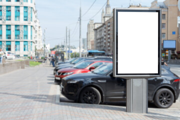 Vertical billboard for advertising and text. Blured parking area next to the road. Mock-up.