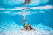 Young Boy Swim And Dive Underwater. Under Water Portrait In Swim Pool. Child Boy Diving Into A Swimming Pool. Summer Kids In Water In Pool Underwater.