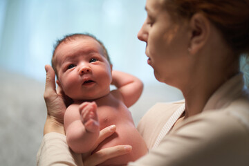 Wall Mural - Newborn baby. mother holding baby in her arms flirting with him.