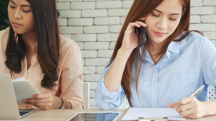 Wall Mural - Two businesswomen team meeting using laptop at company office desk. Two young Female freelance reading financial graph charts Planning analyzing marketing data. Asian people team working office firm.