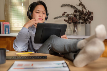 Wall Mural - asian woman cross leg on table when video conference with team at home