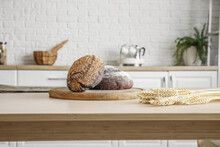 Cutting Board With Loaves Of Fresh Bread On Table In Kitchen