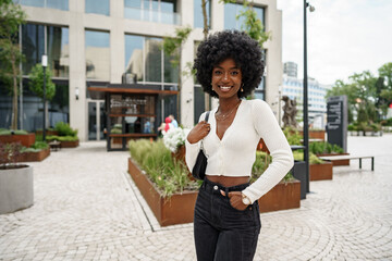 Portrait of young african woman with afro hairstyle smiling in urban background