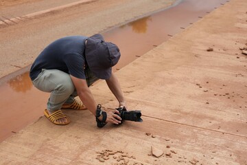 Wall Mural - A photographer stoops to take a low angle shot on a concrete road