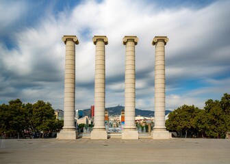 Wall Mural - Four Columns sculpture in Barcelona,Spain under sunlight with cloudy sky in the background