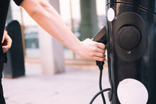 Hands of man pulling out electric car charger from electric station