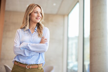 Smiling Businesswoman With Arms Crossed Standing In Office